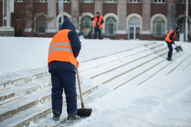 Crew clearing snow on commercial building steps